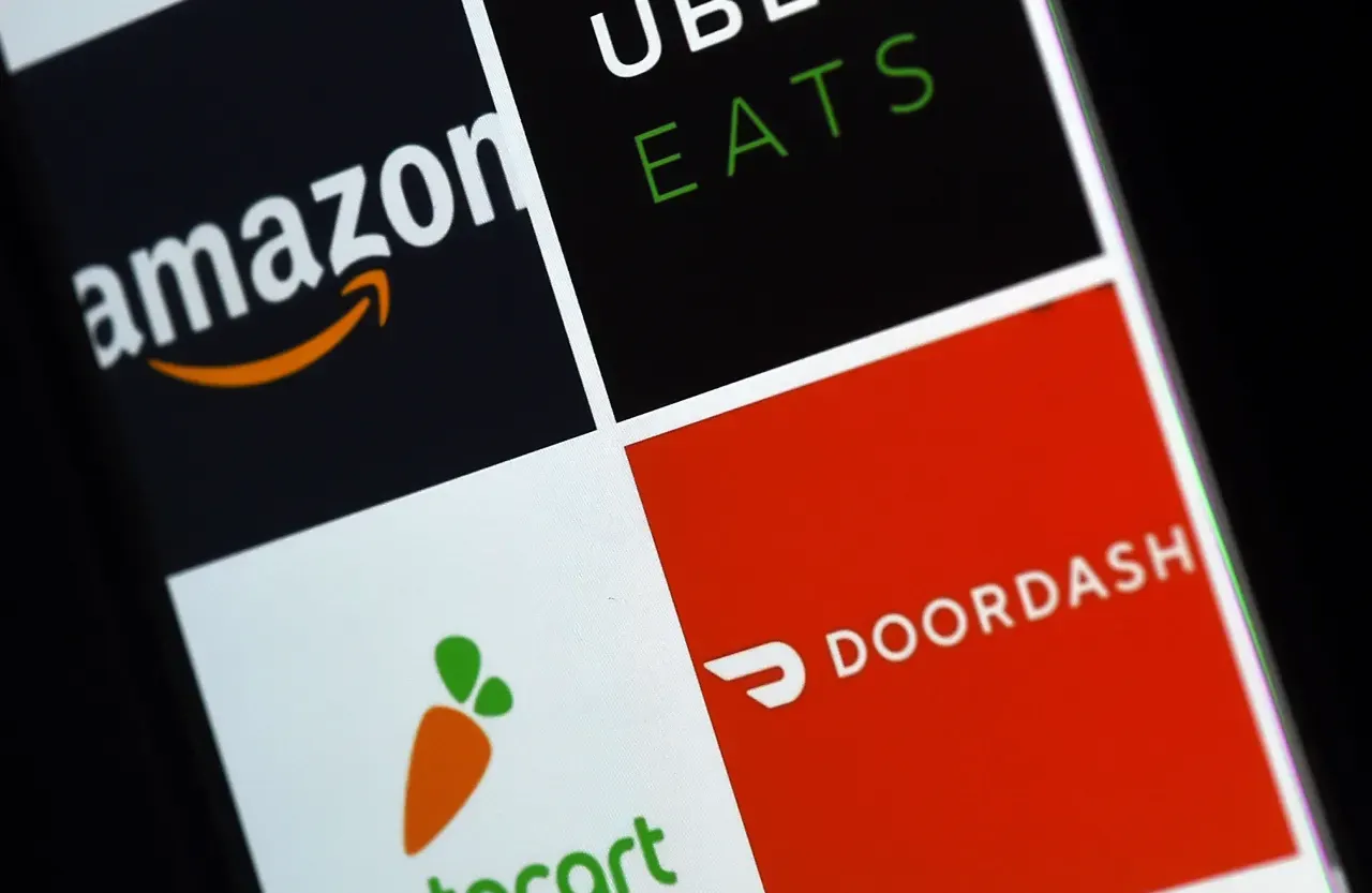 Phone screen showing Amazon, Uber Eats, Instacart and DoorDash app logos in tiles.