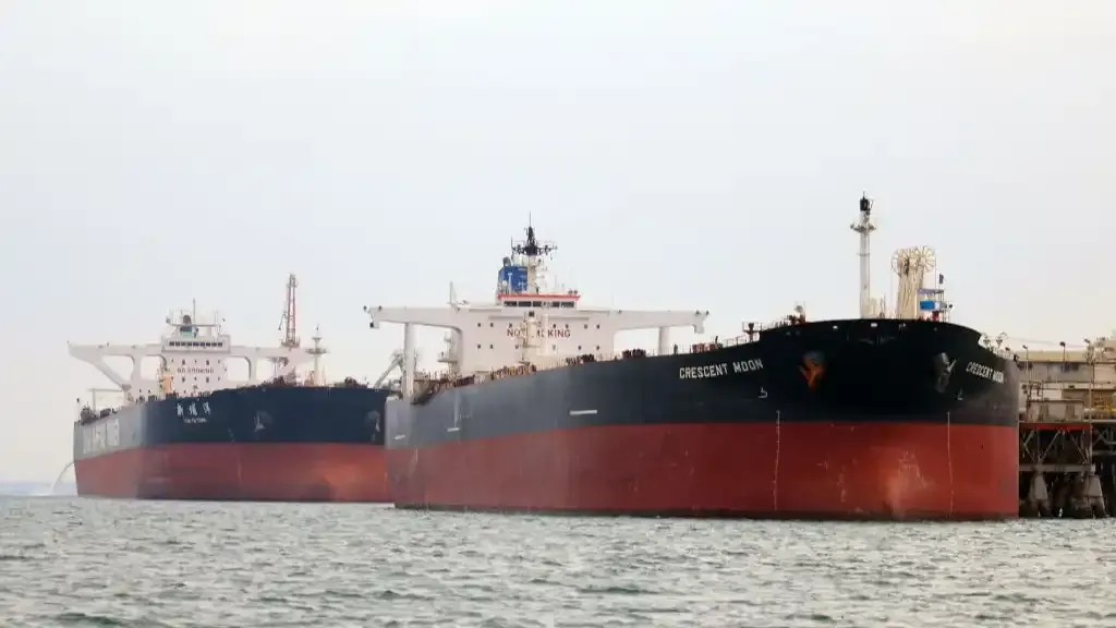 Two large crude oil tankers moored side by side at an offshore terminal under grey sky.