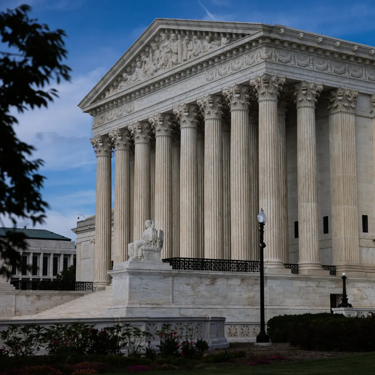 Exterior of the Supreme Court building with marble columns, pediment sculpture and seated statue.