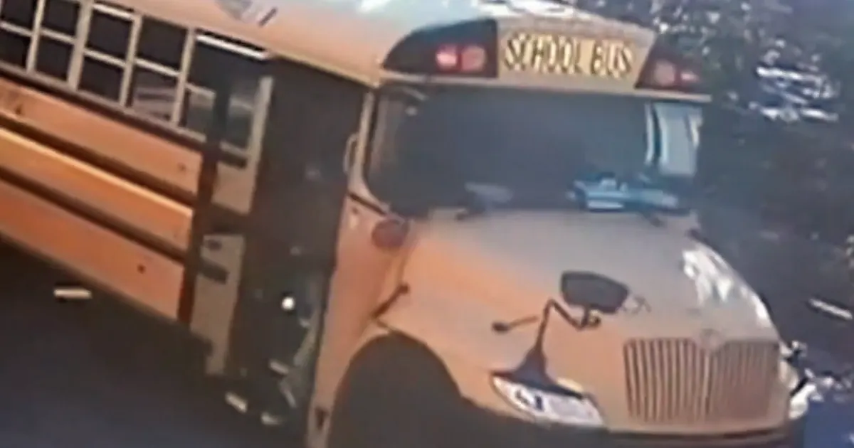 Yellow school bus with SCHOOL BUS sign, stopped at curb, blurry dashcam-style footage.