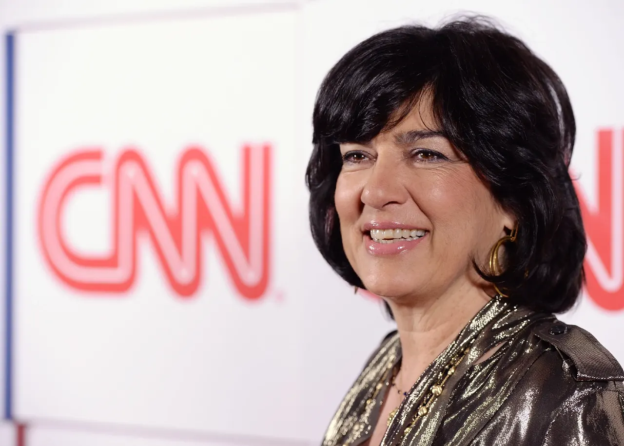 Smiling woman with dark bob and gold hoop earring in front of CNN logo backdrop