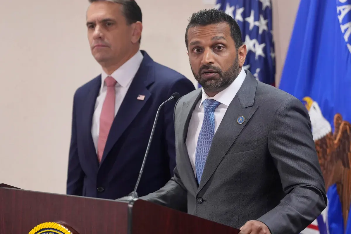 Two men in suits at a podium before a US flag and an agency seal.