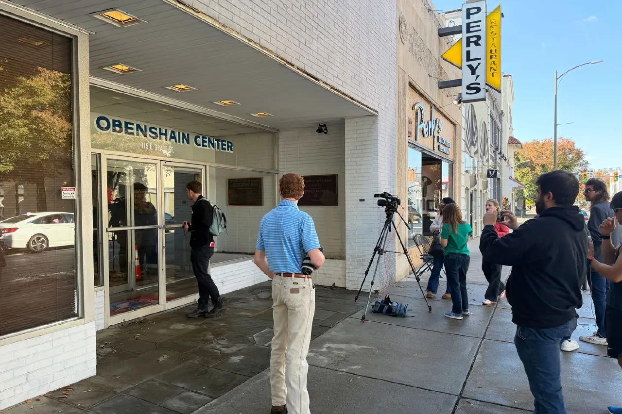 Reporters with a camera on tripod outside the Obenshain Center building in Richmond
