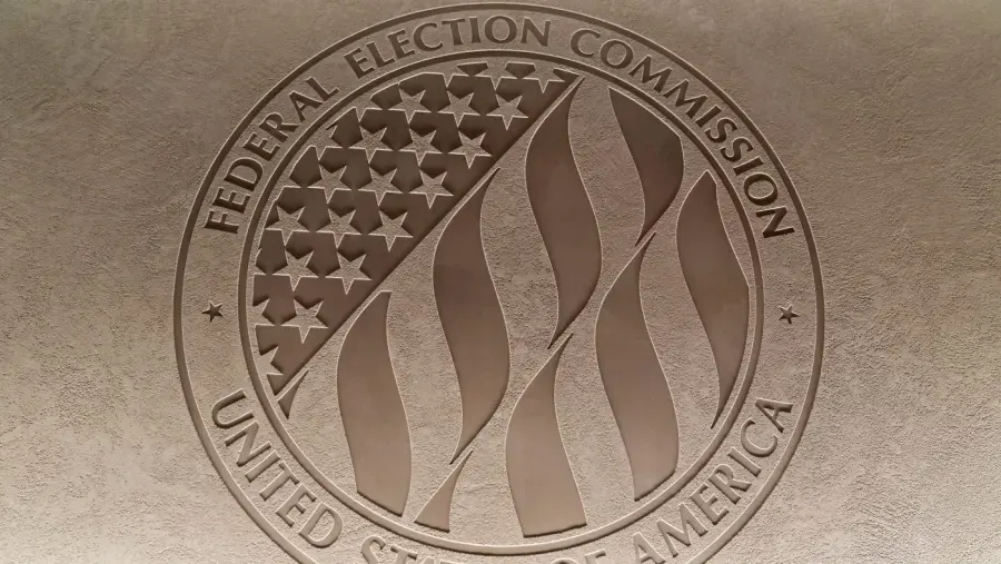 Engraved Federal Election Commission seal with American flag motif on textured stone wall.