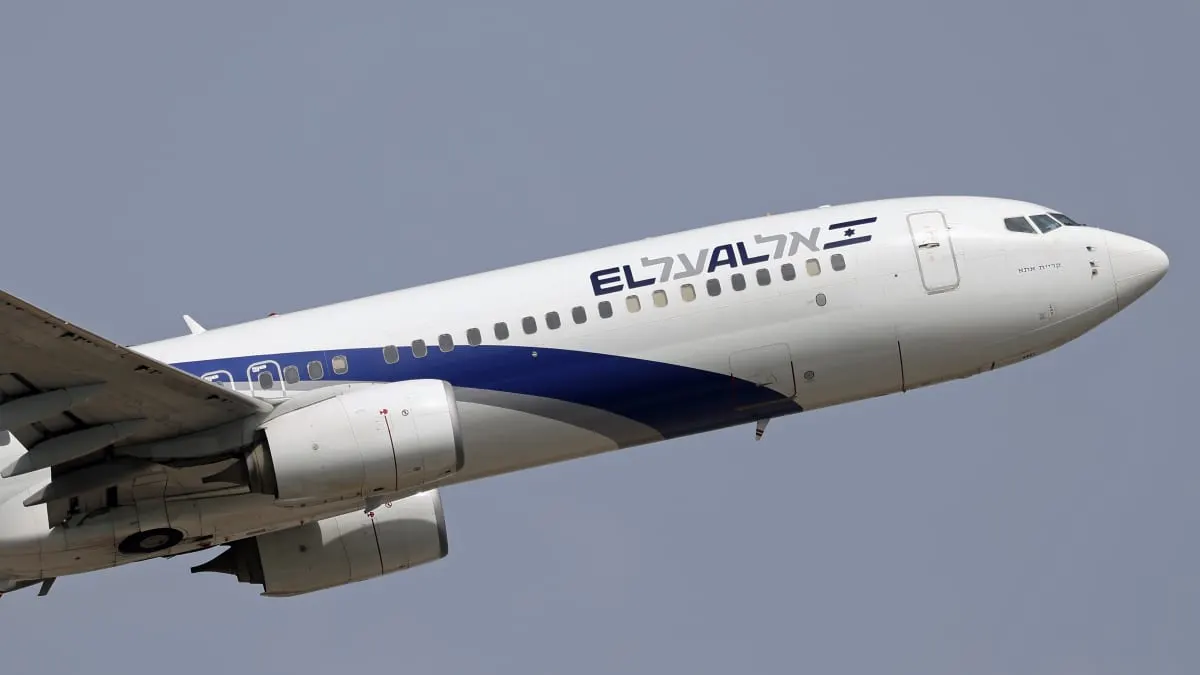 El Al passenger airliner with Israeli flag logo climbing against a grey sky.