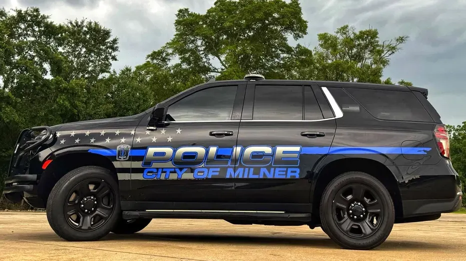 Black police SUV with 'POLICE City of Milner' markings and blue stripe on a paved lot.