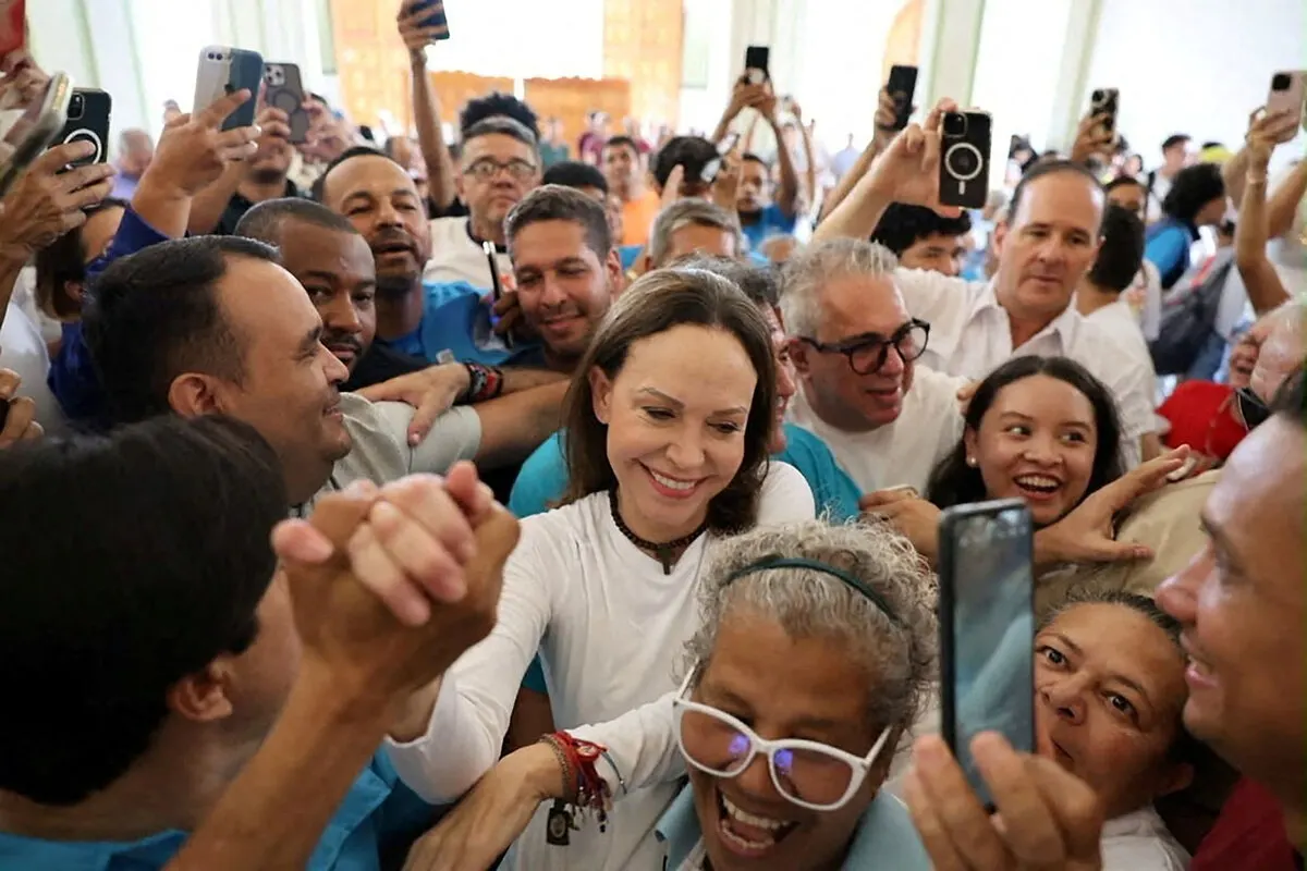 Smiling woman in white surrounded by a jubilant crowd, many raising phones to record.
