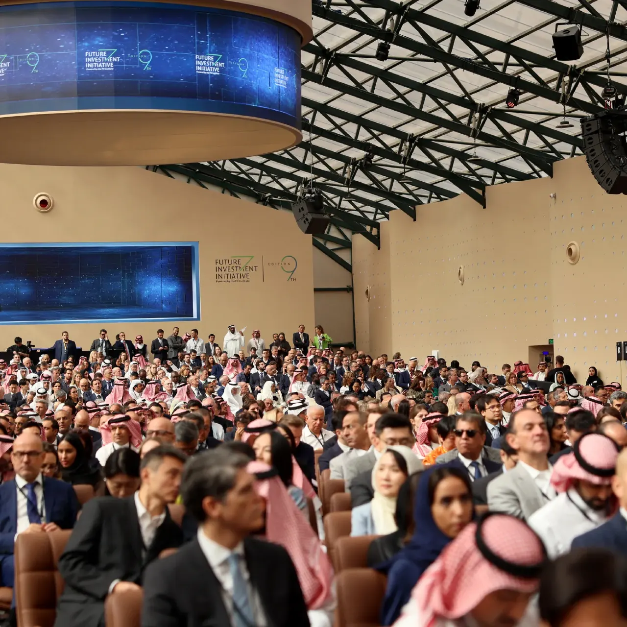 Large seated audience at Future Investment Initiative conference hall, screens showing event branding