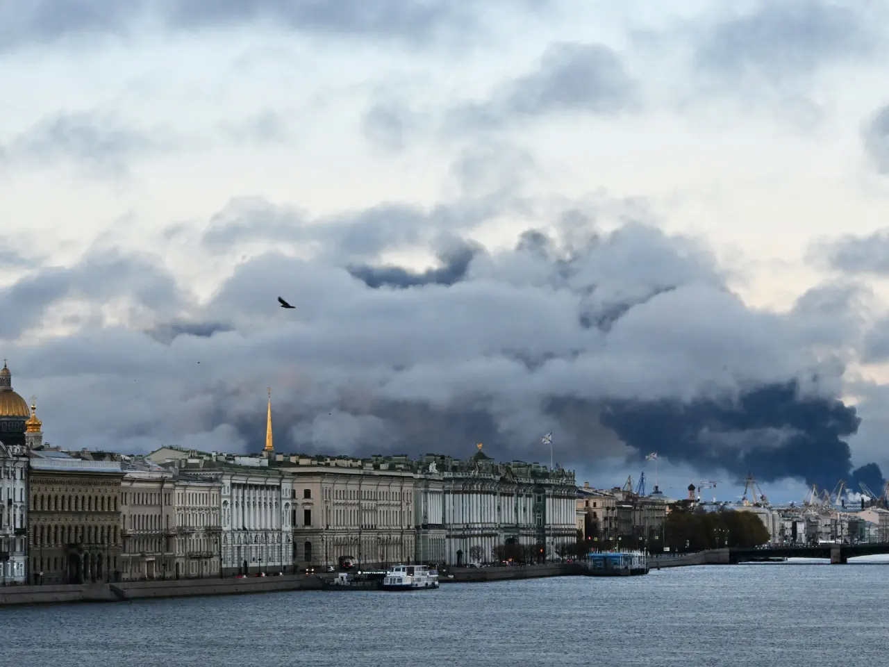 Dark smoke plumes rising over St Petersburg waterfront buildings and river on a cloudy day