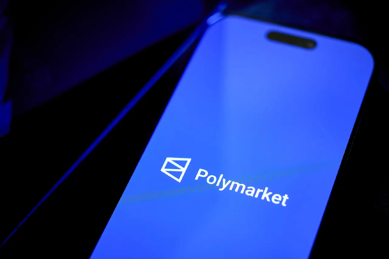 Smartphone screen showing the Polymarket logo on a blue background in dim lighting