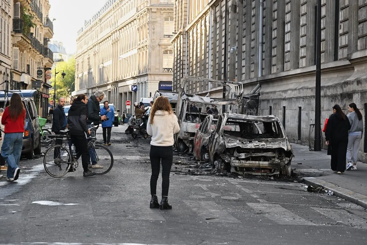 Street lined with burned-out vehicles and pedestrians on a Paris boulevard after unrest