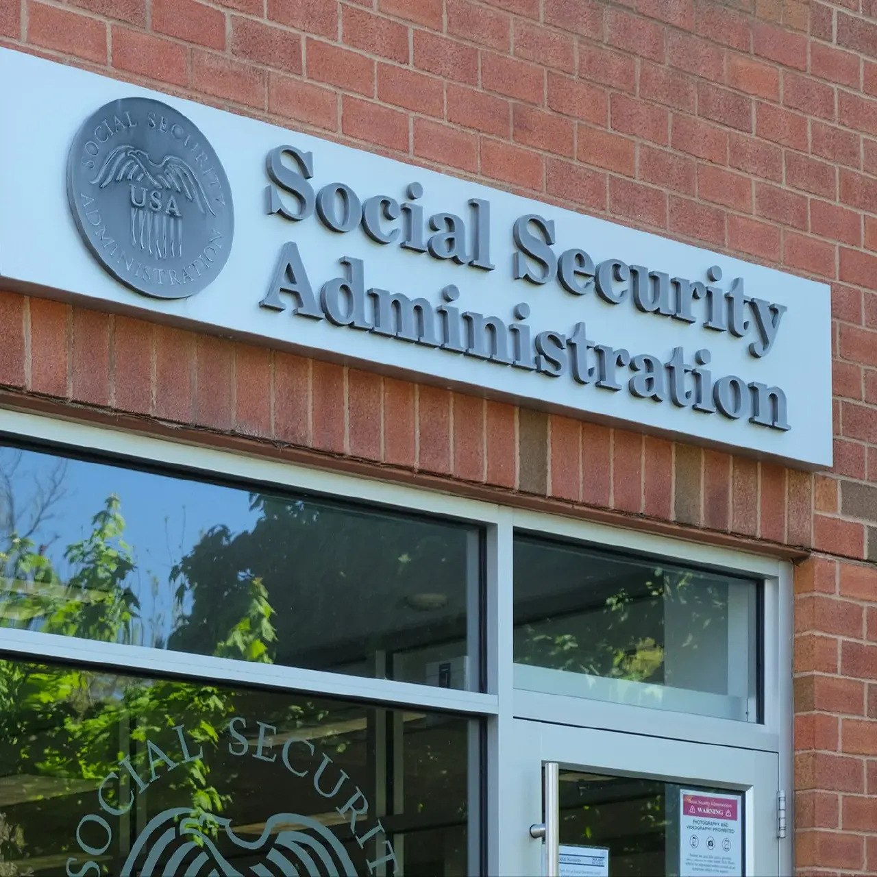 Brick building entrance with Social Security Administration sign and agency seal above glass doors.