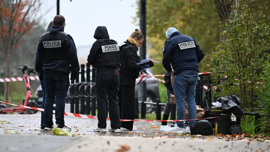 Police investigators in jackets marked Police Judiciaire behind crime-scene tape on a street, with a luggage pile.
