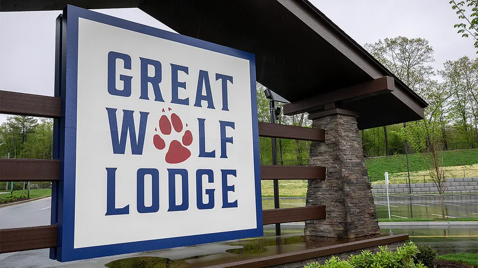 Great Wolf Lodge sign with red paw print logo beneath a stone-pillared entrance canopy.