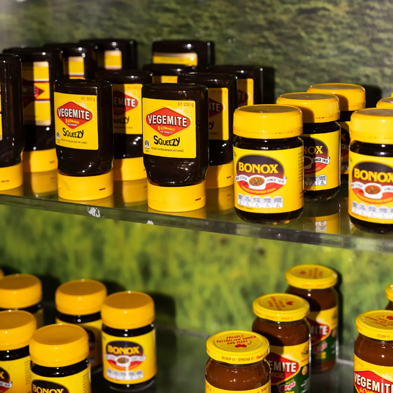 Shelves of Vegemite squeezy bottles and Bonox jars on a glass display shelf