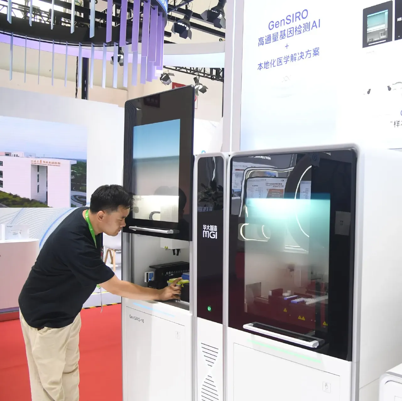 Man in black shirt operating MGI gene sequencing machines at an exhibition booth with Chinese signage.