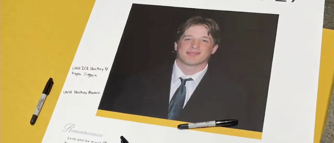 Memorial poster with a portrait photo of a smiling young man and handwritten tributes, markers on table