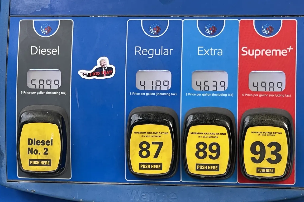 Gas pump display showing diesel and gasoline prices, with a small sticker of a cartoon figure.