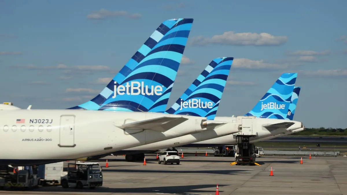 Several JetBlue airliners with blue tail logos parked on an airport tarmac