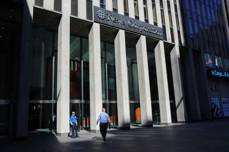 News Corporation building facade with columns and two pedestrians walking at entrance