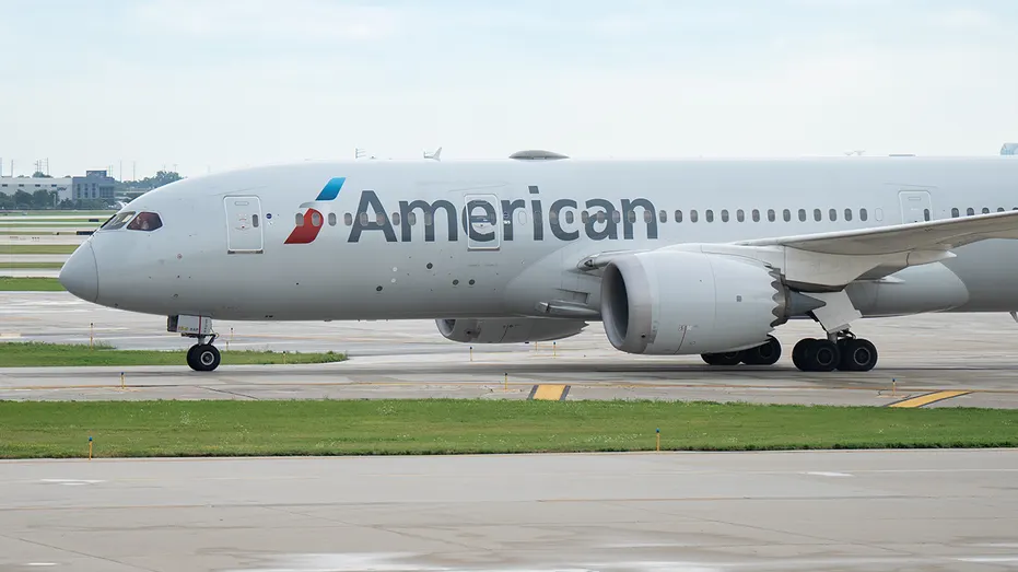 American Airlines jet taxiing on airport tarmac, showing livery and engines.