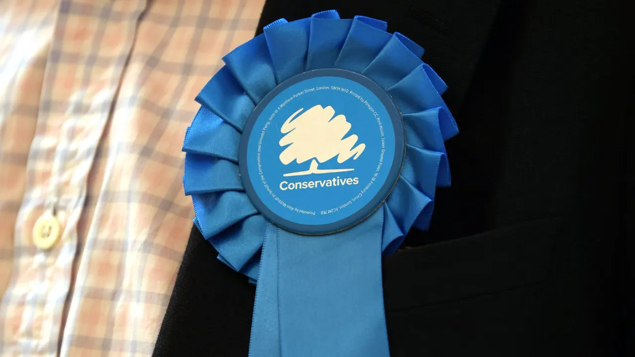 Blue rosette with Conservatives logo pinned to a dark jacket lapel