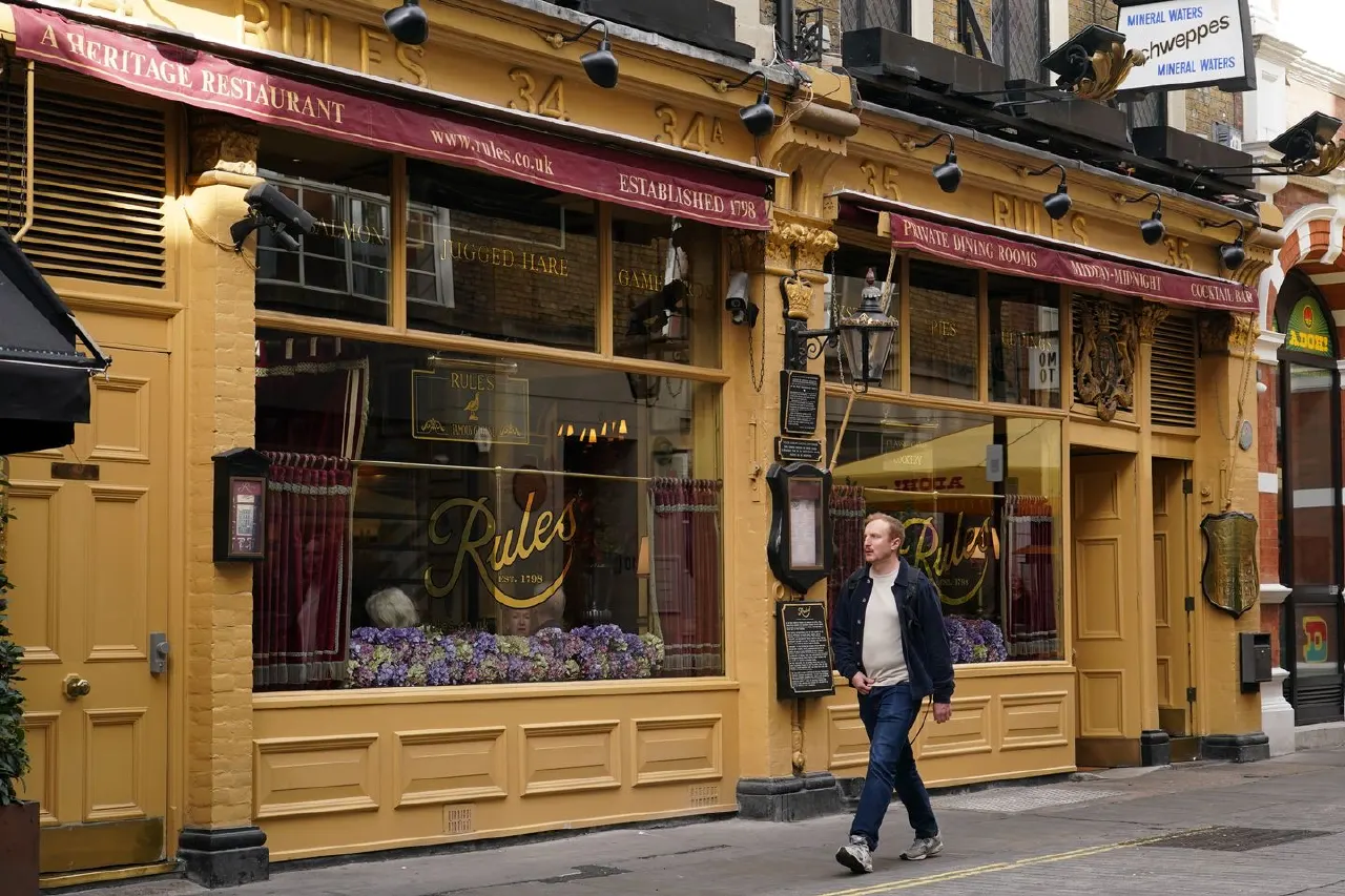 Exterior of Rules restaurant on a street, with a man walking past the entrance.