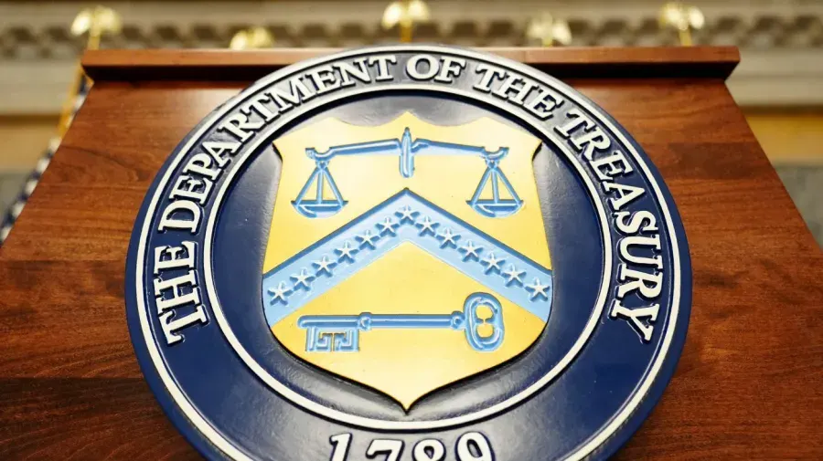 Department of the Treasury seal mounted on a wooden podium, with 1789 visible.