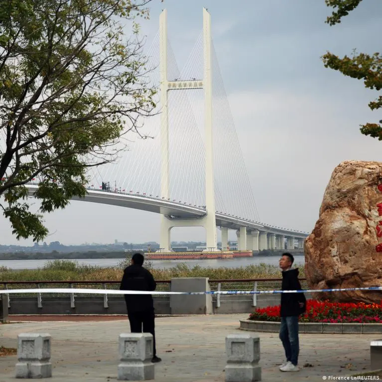 Cable-stayed bridge over river with blue police tape and two people on a riverside promenade.