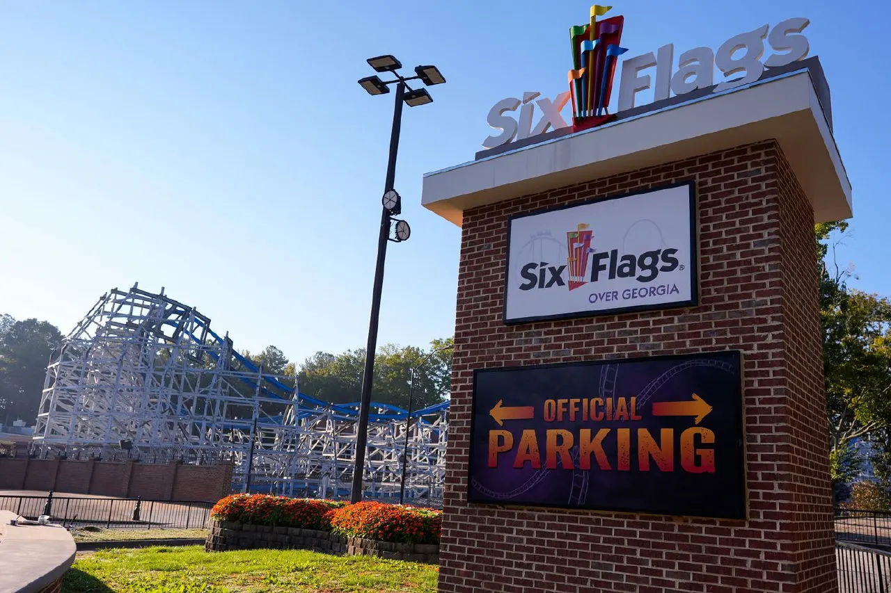 Six Flags Over Georgia entrance sign with official parking board and roller coaster structure behind