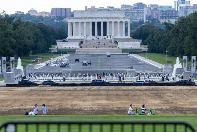 Lincoln Memorial and drained Reflecting Pool area with small figures and parked cars in Washington.