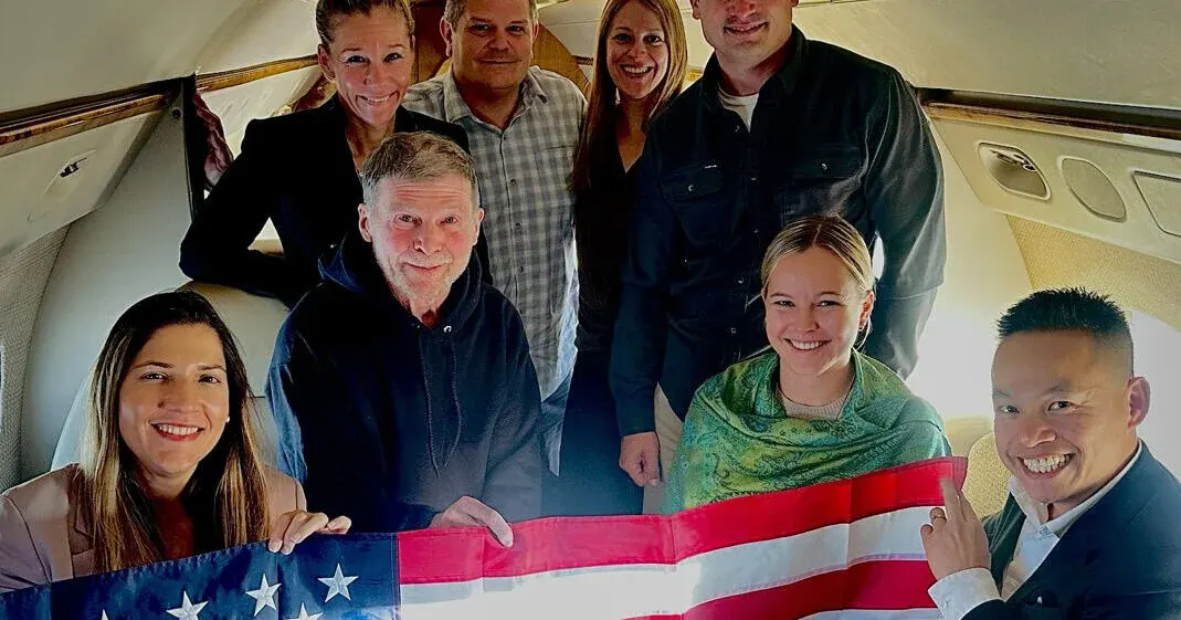 Smiling group inside a private aircraft cabin holding an American flag.