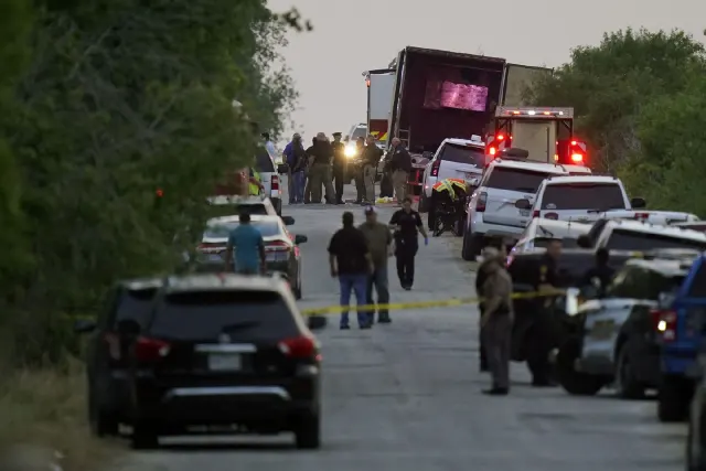 Law enforcement officers and vehicles on a rural road beside a parked tractor-trailer at dusk.