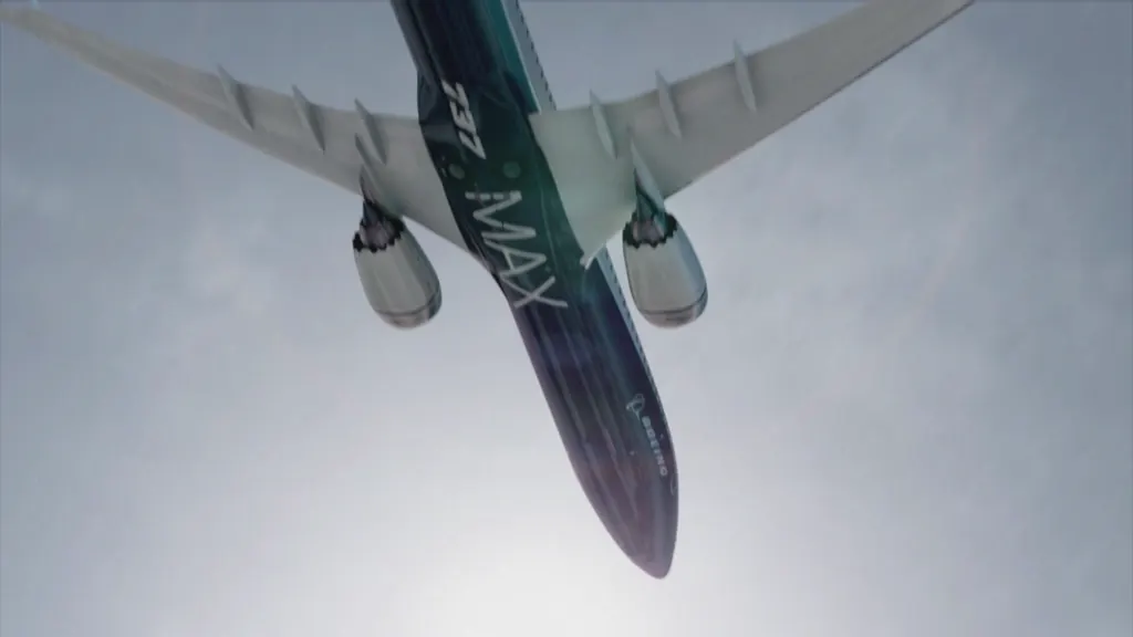 Low-angle view of a Boeing 737 MAX jet in flight against a cloudy sky.