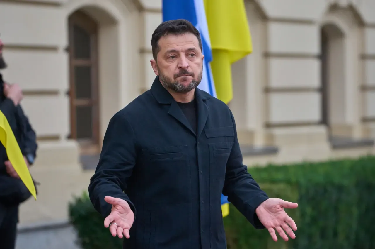 A bearded man in a dark jacket gestures with open hands, a blue and yellow flag behind him.