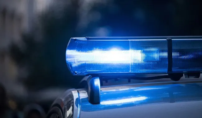 Blue police light bar glowing on top of a vehicle at night
