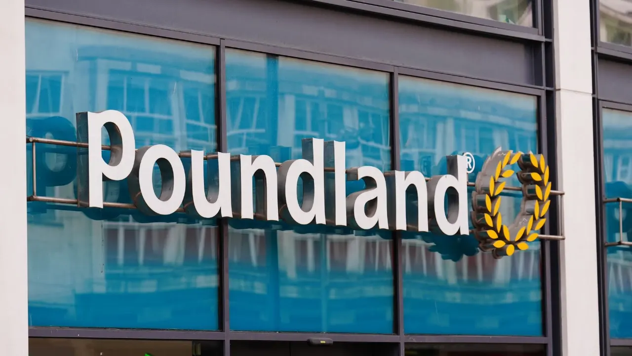 Poundland store sign with logo on a glass building facade, reflecting windows