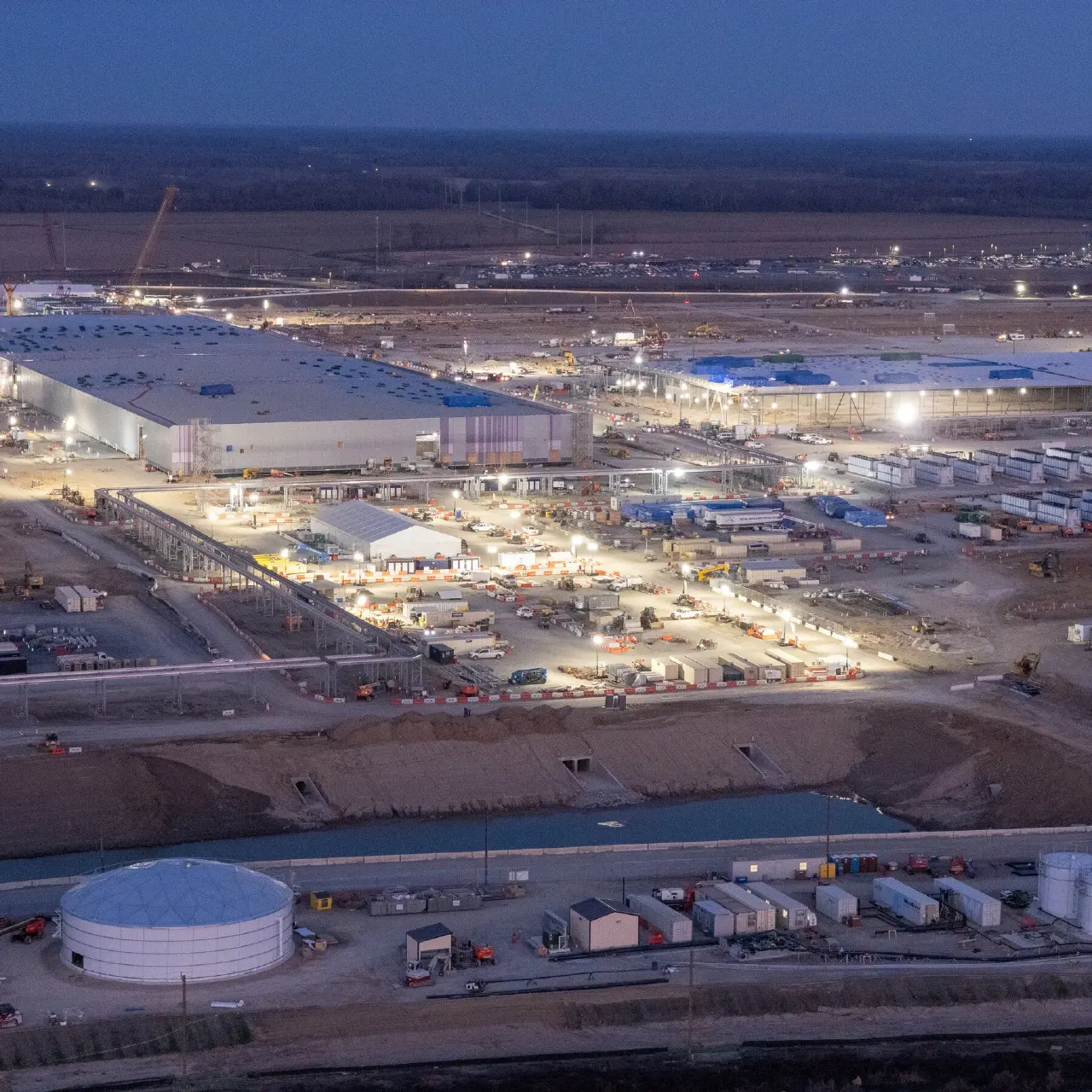 Aerial dusk view of a large data center construction site with buildings and equipment.