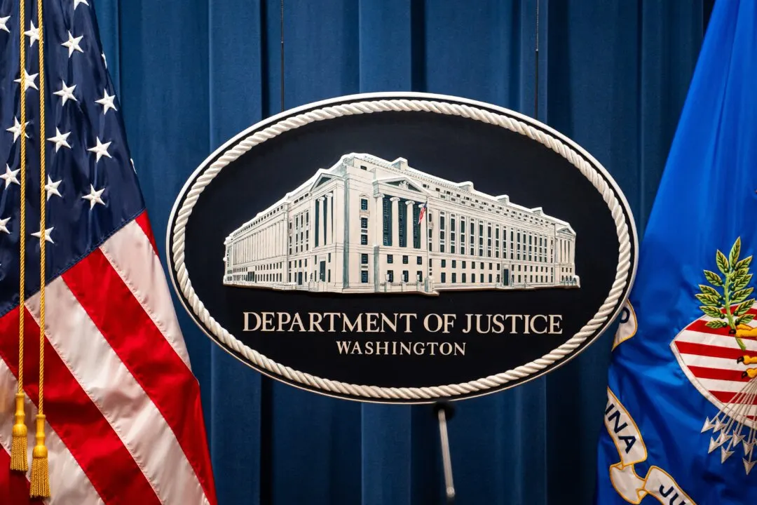 Department of Justice seal sign with building illustration, flanked by American and DOJ flags.