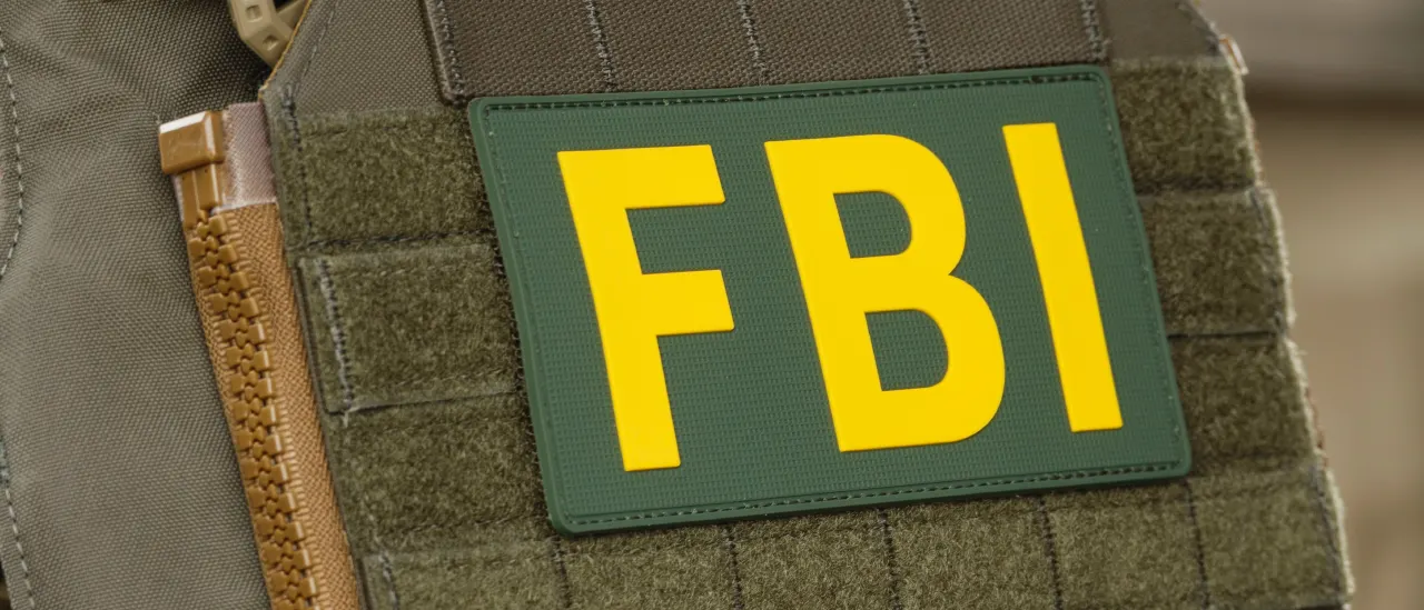 Close-up of green tactical vest patch reading FBI in yellow letters