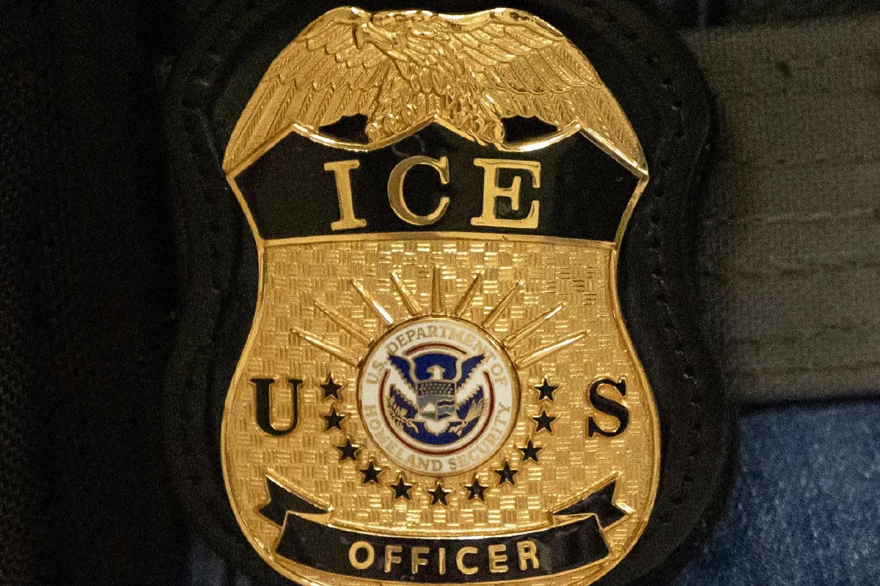 Close-up of a gold ICE officer badge with the DHS seal and eagle emblem.