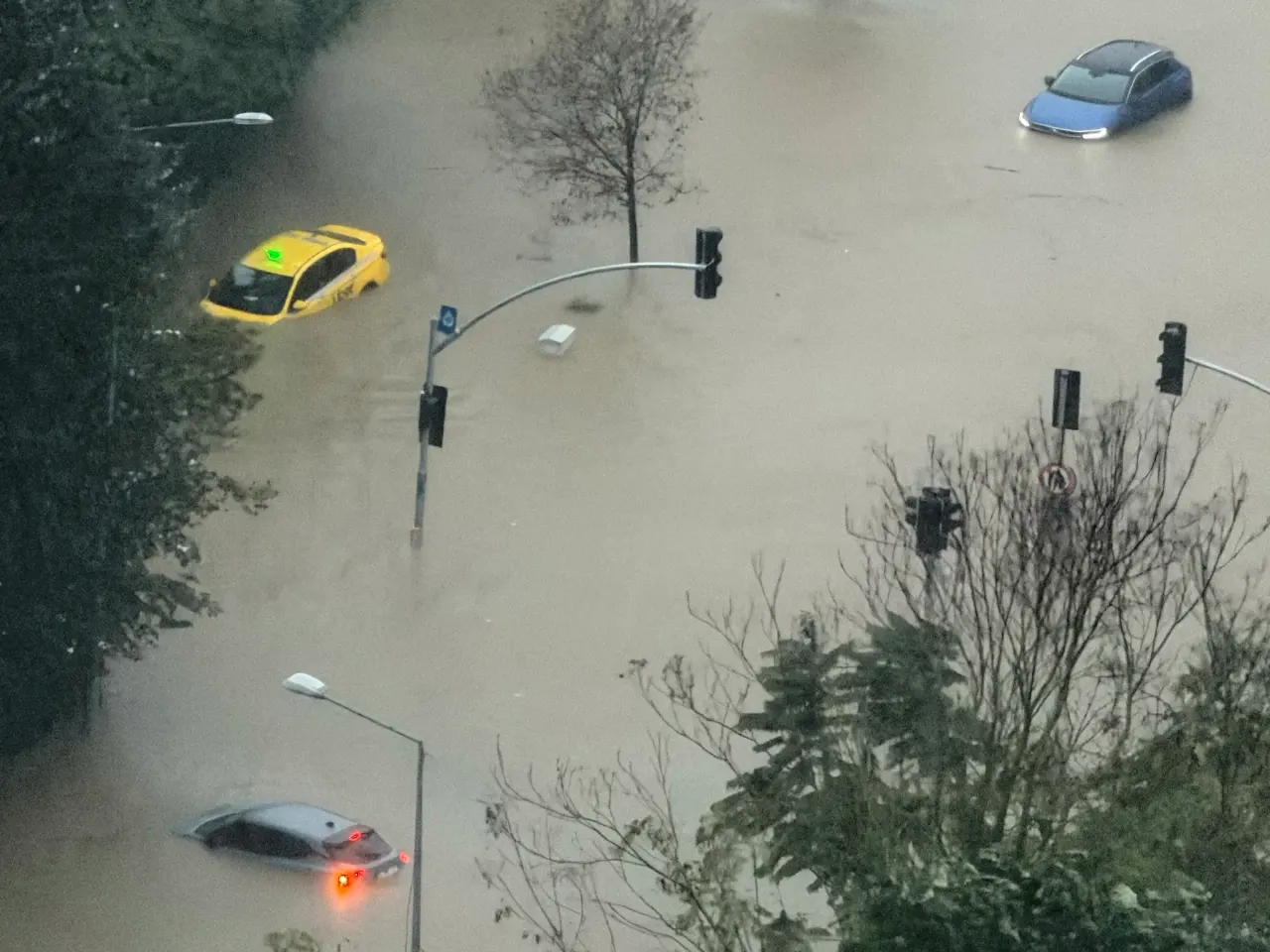 Aerial view of flooded city street with submerged cars, traffic lights and trees.