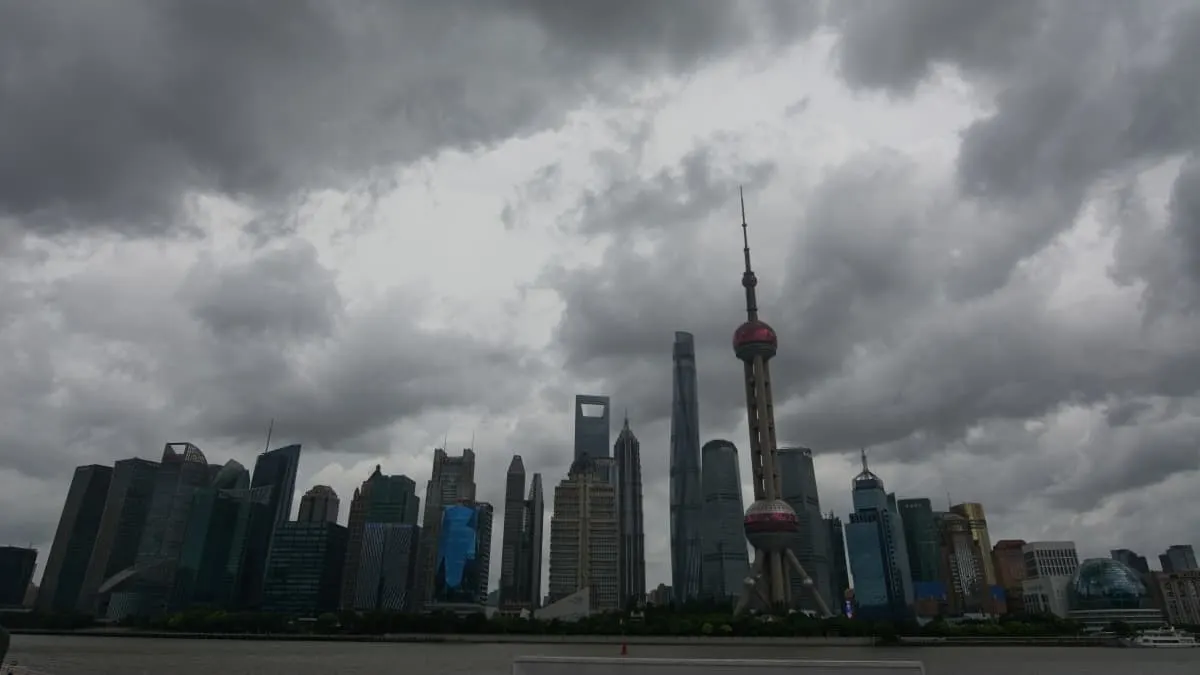 Shanghai Lujiazui skyline under heavy grey clouds beside the Huangpu River.