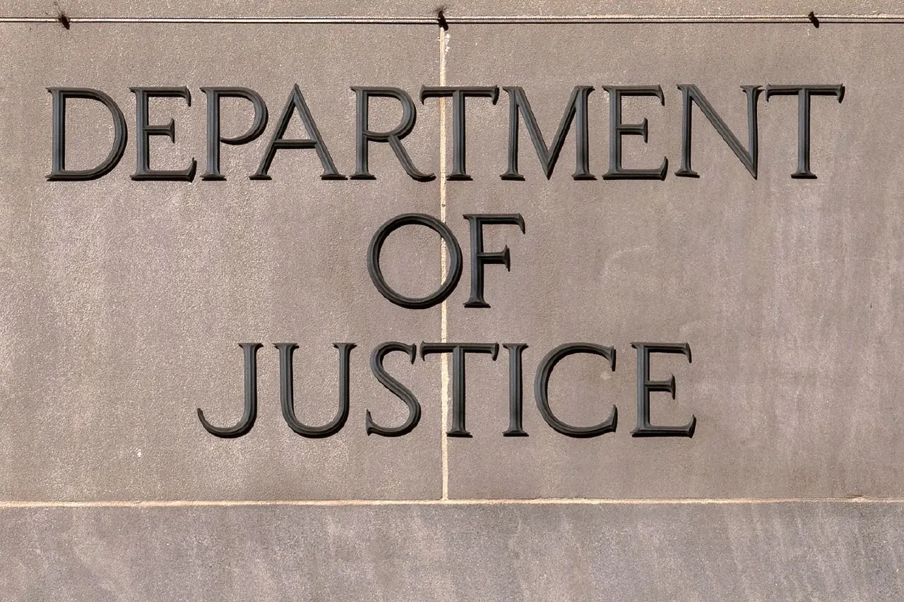 Carved stone lettering reading "Department of Justice" on a concrete building facade.