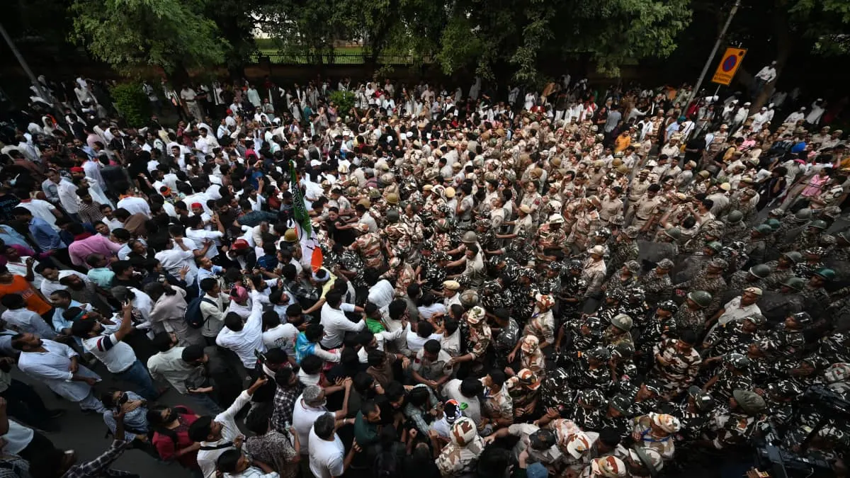 Aerial view of dense crowd with uniformed police officers in tan and camouflage gear on a street