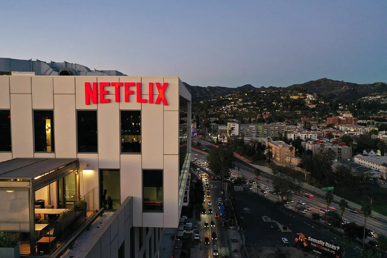 Aerial dusk view of Netflix red logo on white office building above city traffic