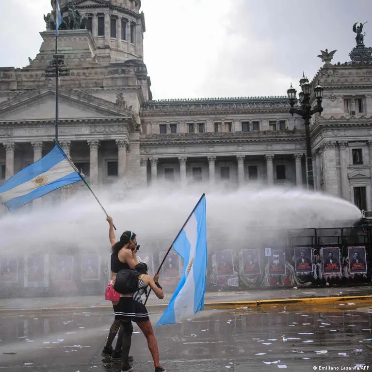 Protesters with Argentine flags face a water cannon blast in front of Congress building.