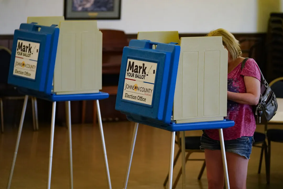 Voter filling out a ballot in a voting booth labeled Johnson County Election Office.
