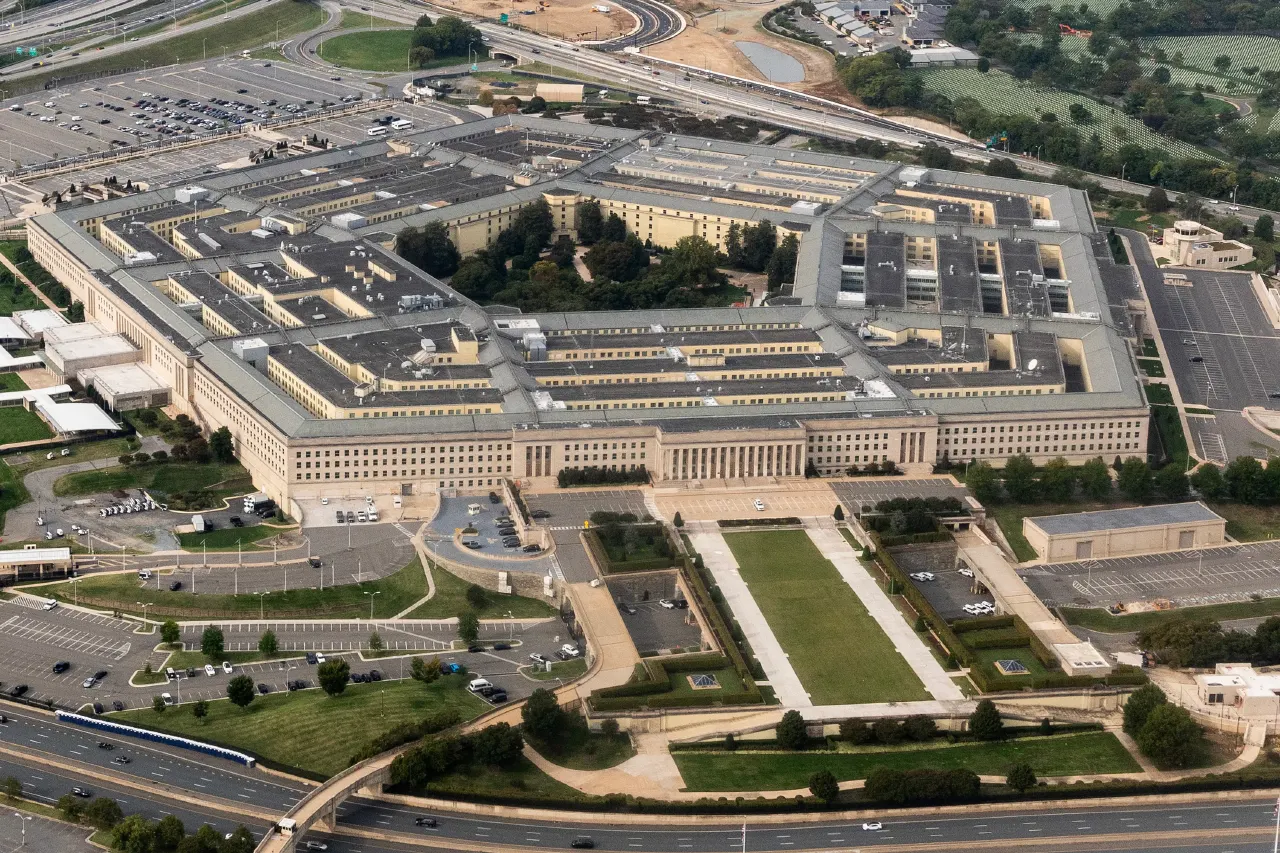 Aerial view of the Pentagon building surrounded by roads, parking lots and green lawns.
