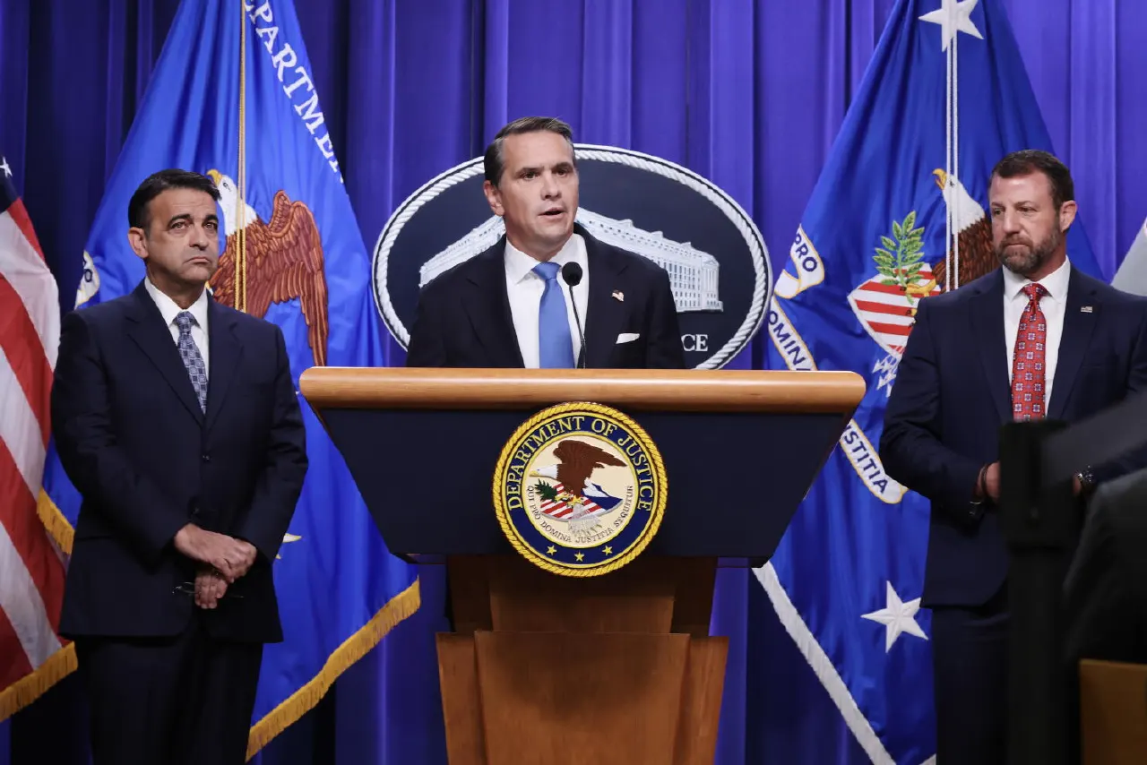 Three men in suits at a podium with Department of Justice seal and flags.
